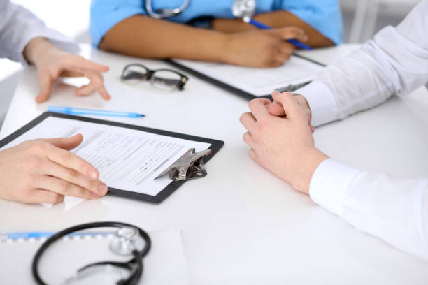 two doctors and male patient discussing medical history at the table, close up