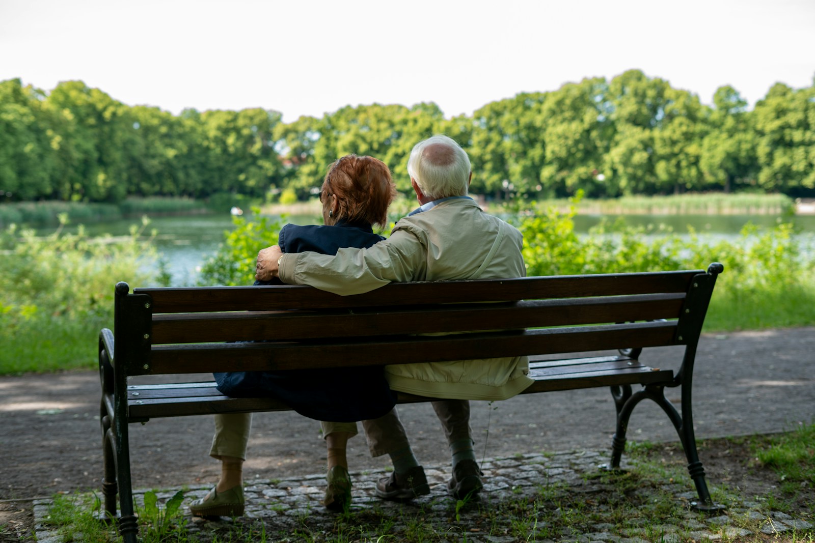 2 women sitting on brown wooden bench during daytime